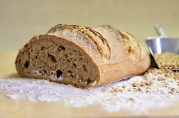 Artisan bread loaf on wooden board with scattered flour and grains